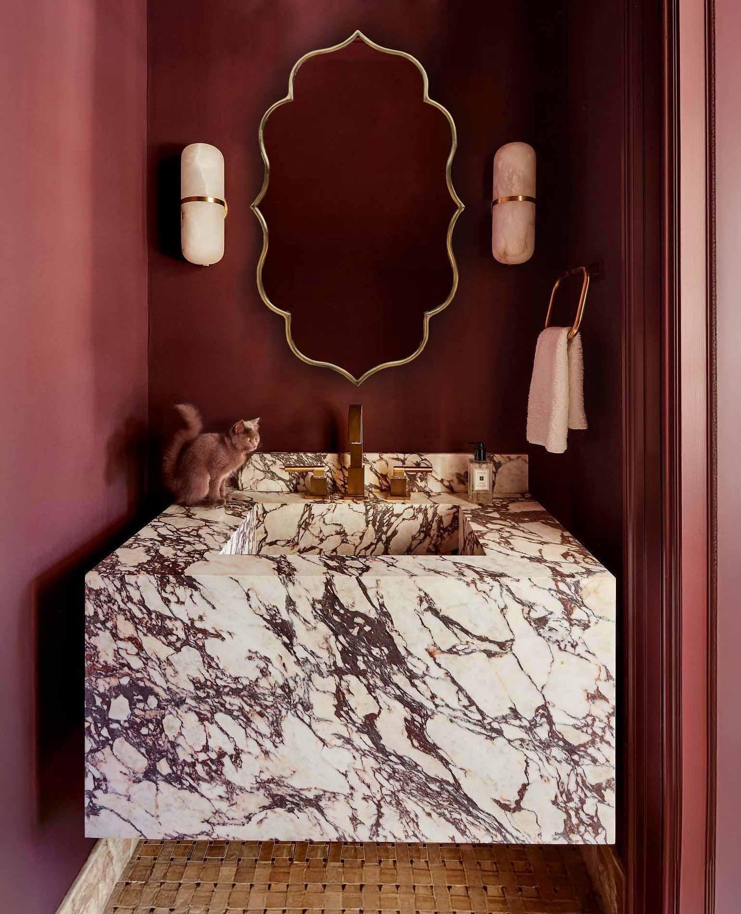 Wall-mounted brass mirror over marble counter.