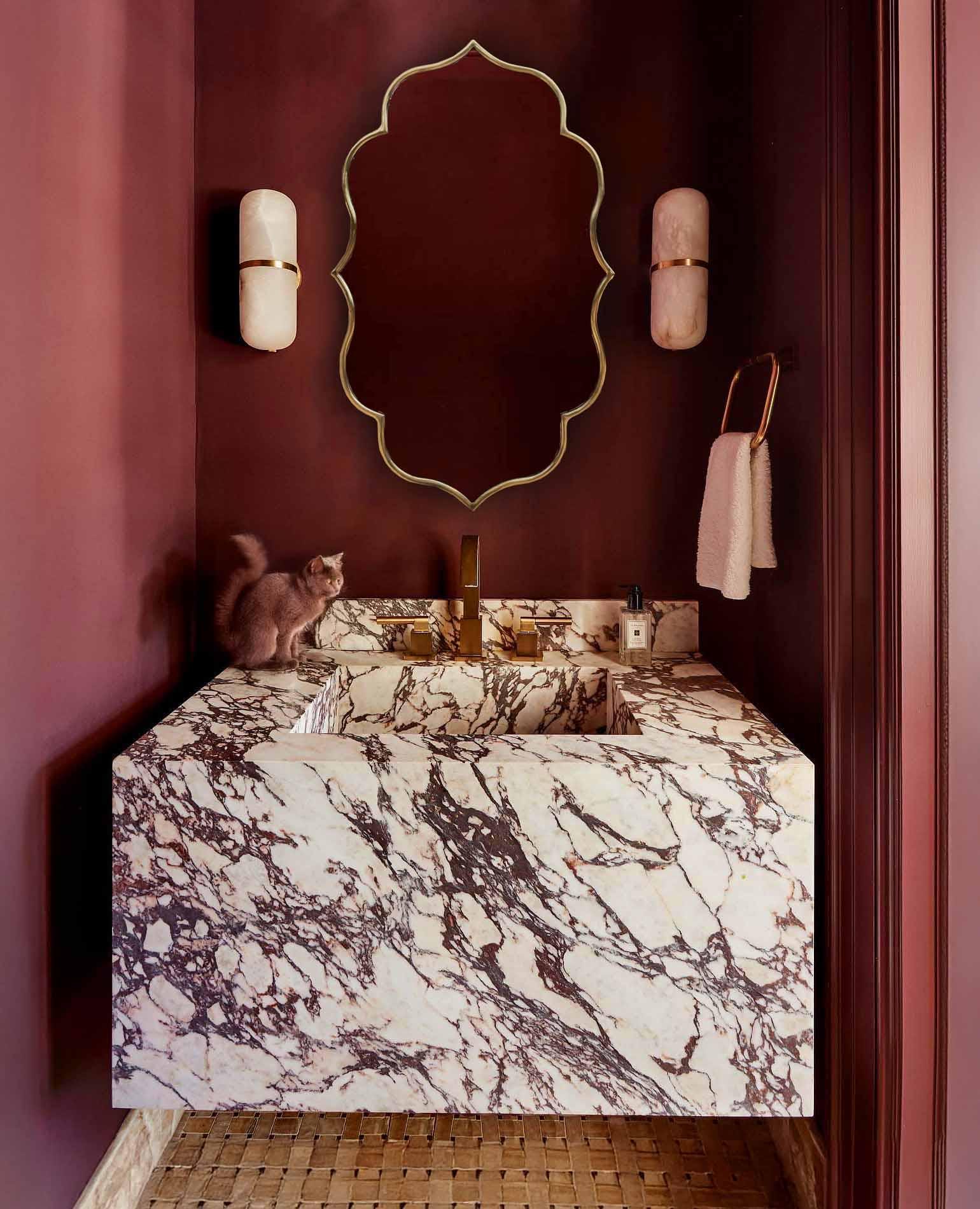 Wall-mounted brass mirror over marble counter.