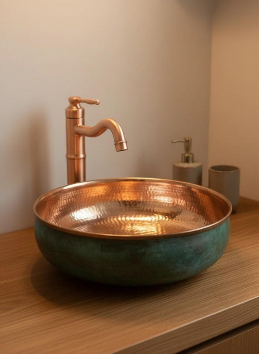 Green patina copper sink with warm copper interior and curved faucet