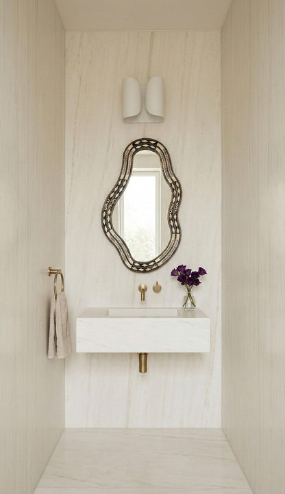 Freeform bone brass mirror above white marble floating vanity