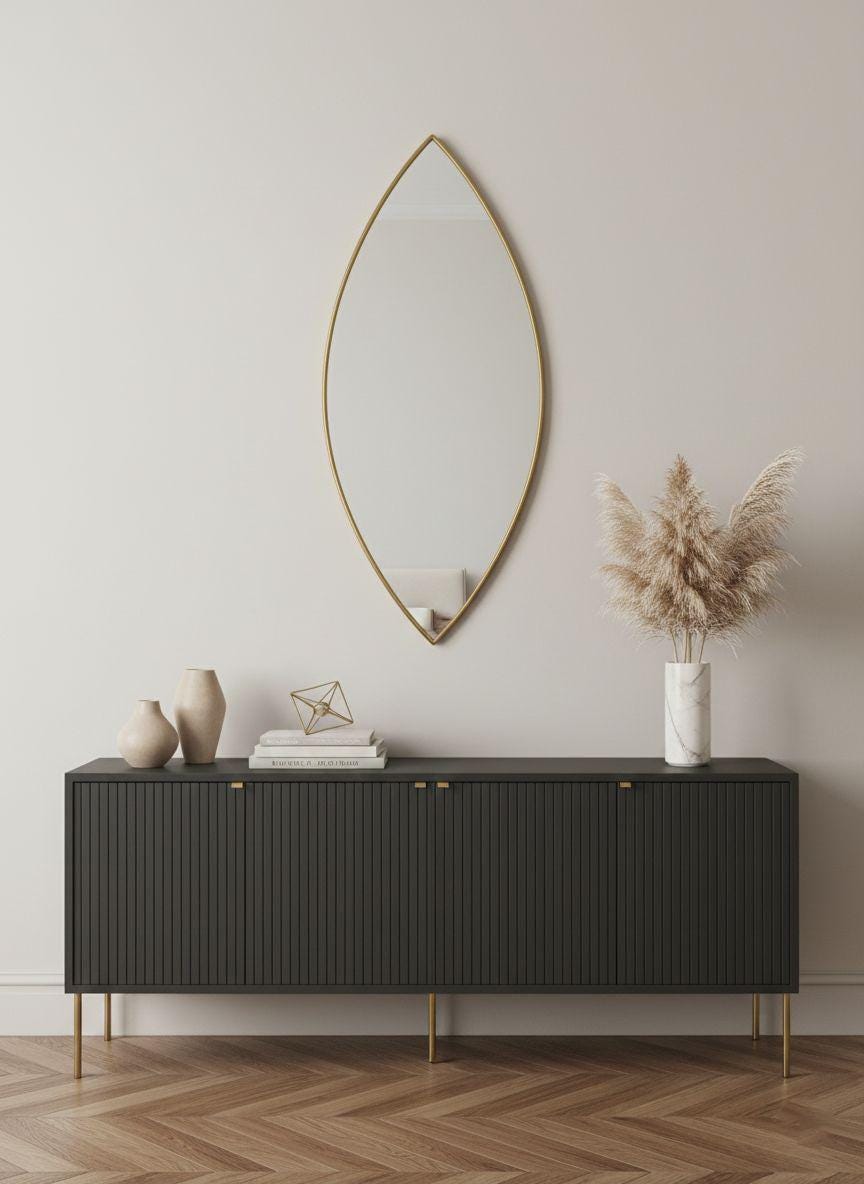 Pointed oval brass wall mirror above black modern sideboard