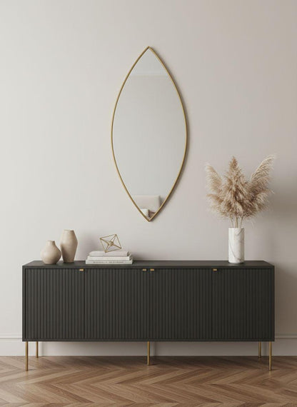 Pointed oval brass wall mirror above black modern sideboard