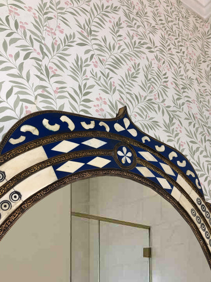 Close-up of the mirror’s arched top with floral wall background.