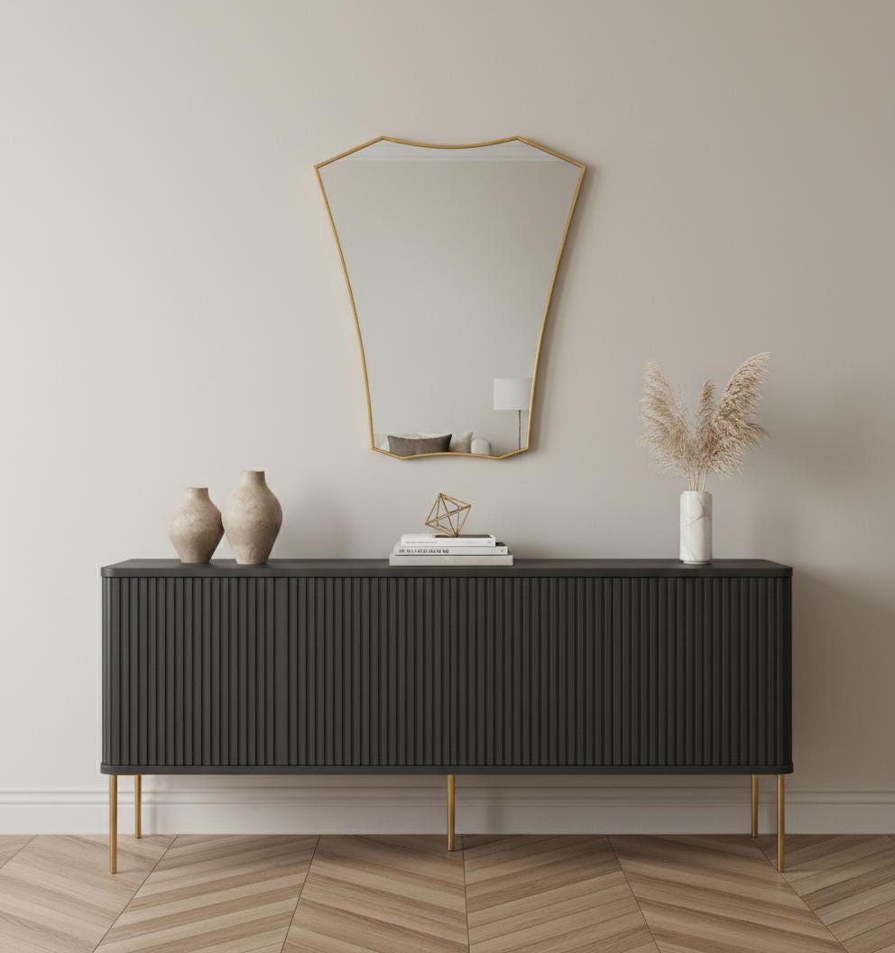 Shield brass wall mirror above modern black sideboard