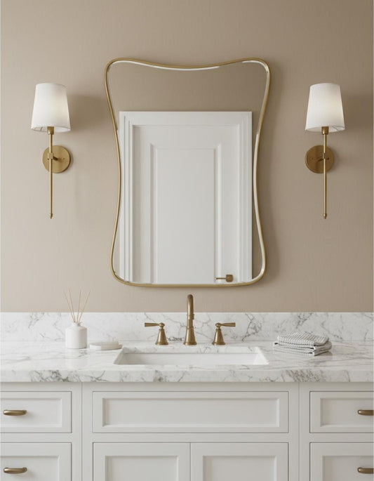Curved brass vanity mirror above white bathroom sink