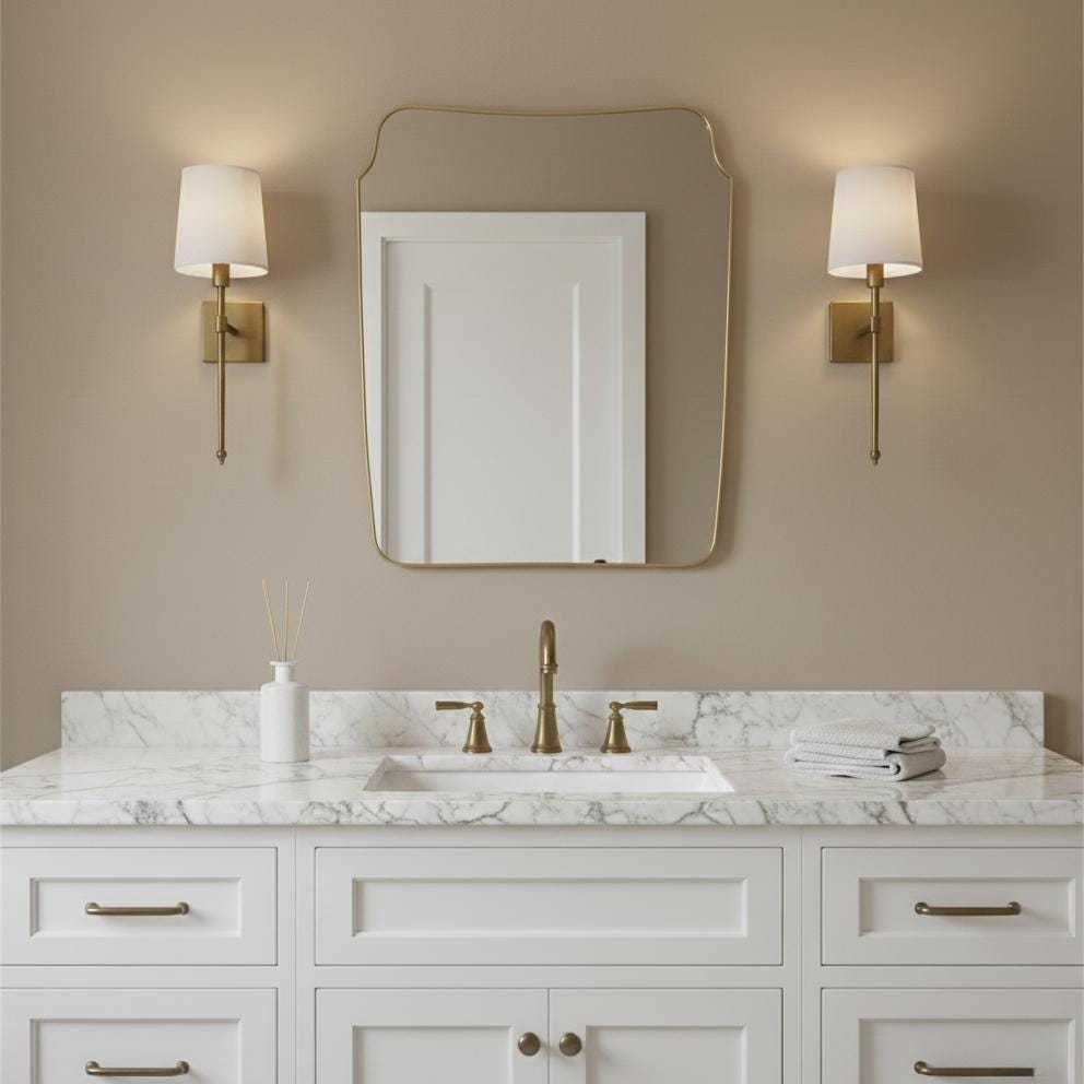 Curved brass vanity mirror with wall sconces in bathroom