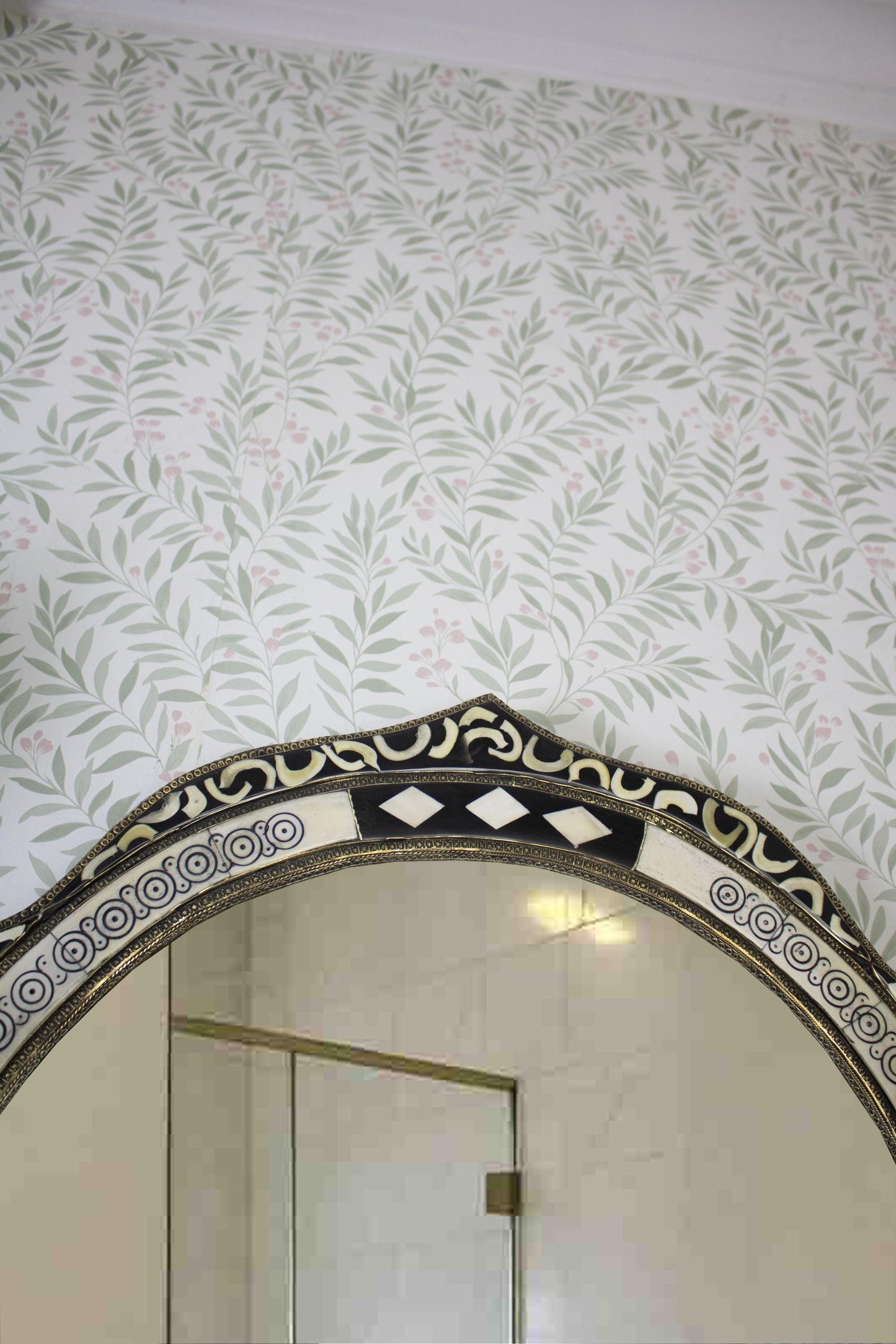 Upper section of the mirror with ornate trim and decorative wall molding.