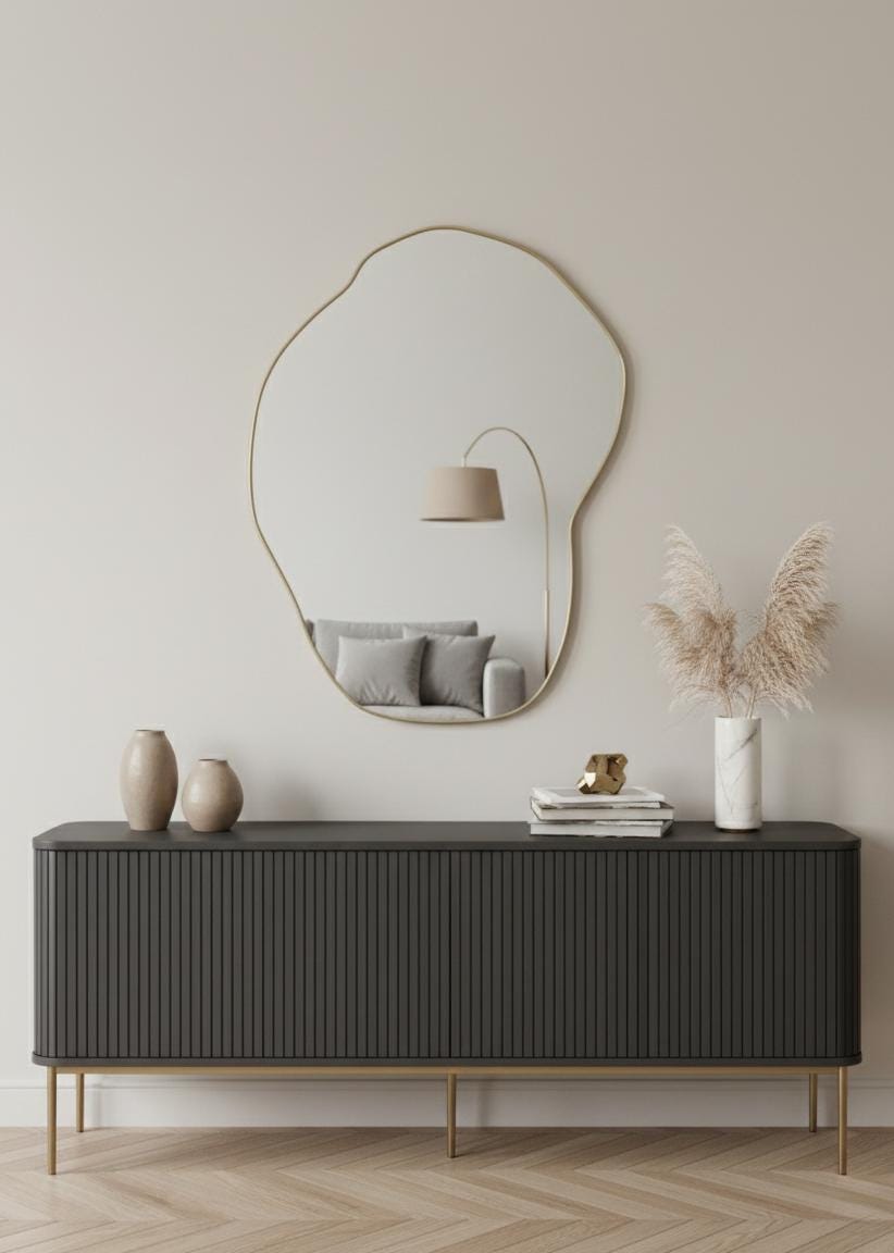 Freeform brass wall mirror styled above modern sideboard