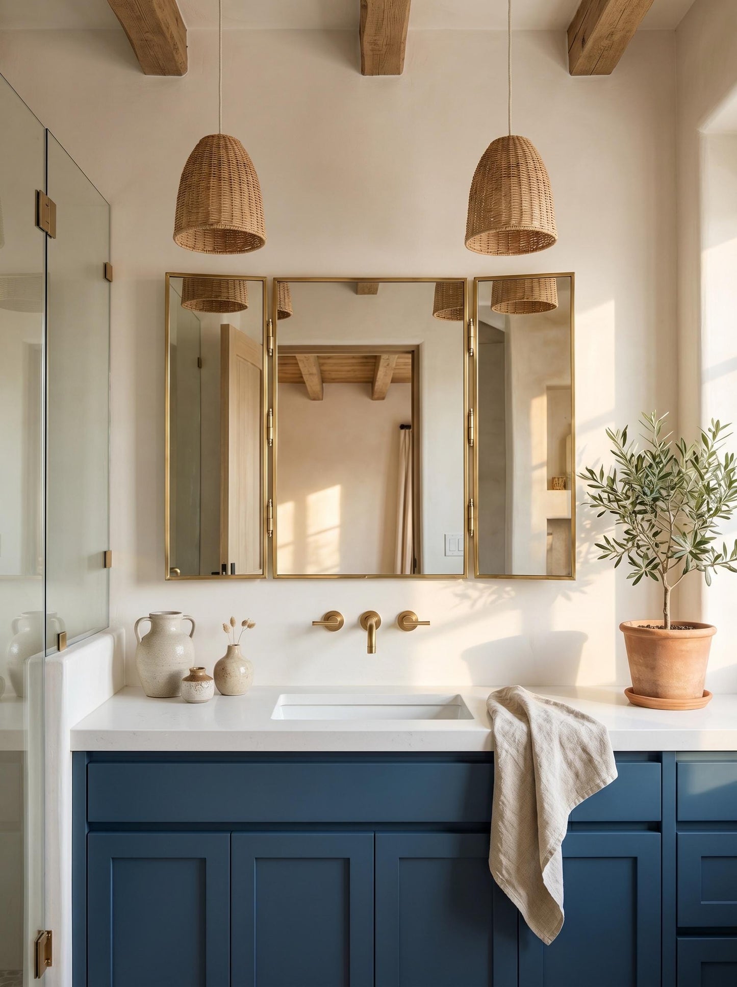 Brass trifold mirror above blue bathroom vanity