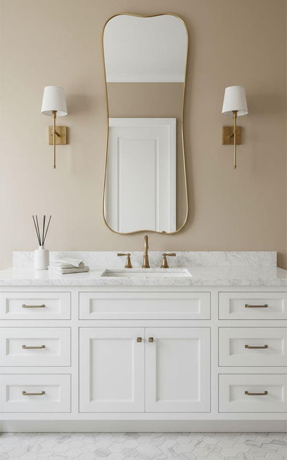 Curved gold vanity mirror above white bathroom sink