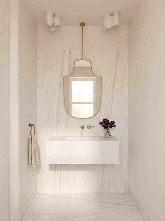 Ceiling-mounted brass mirror above floating white vanity in marble bathroom
