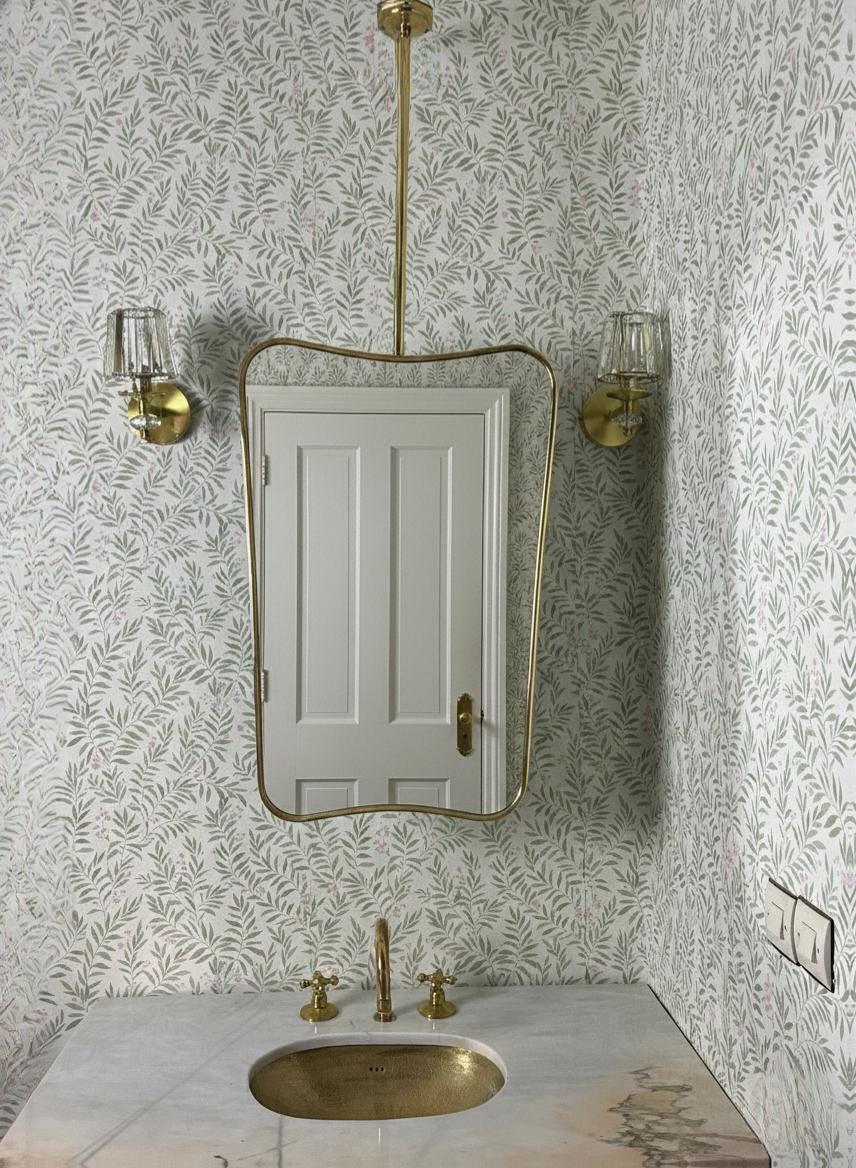 Angled view of suspended brass bathroom mirror