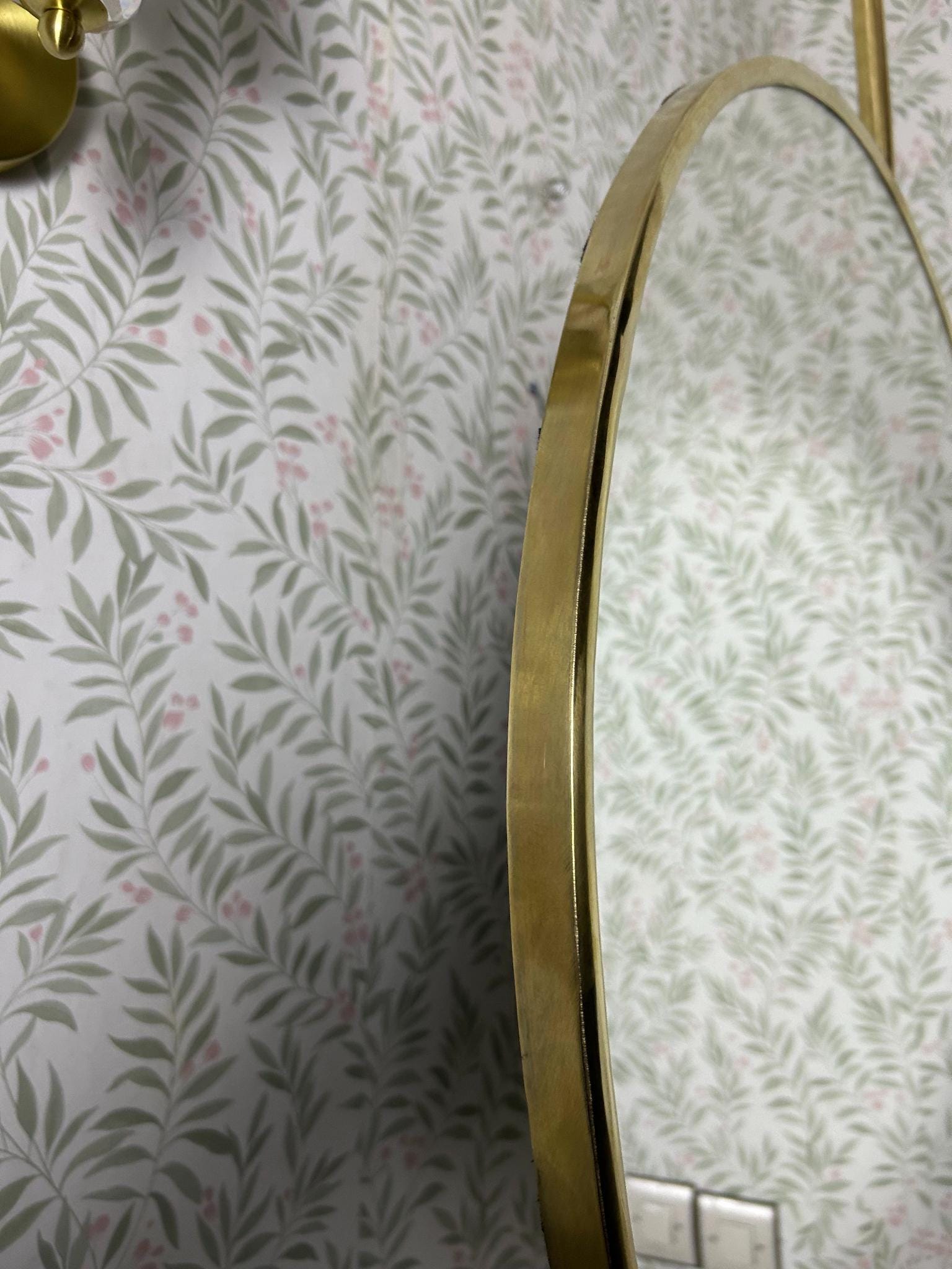 Close-up of brass frame on ceiling hung round mirror