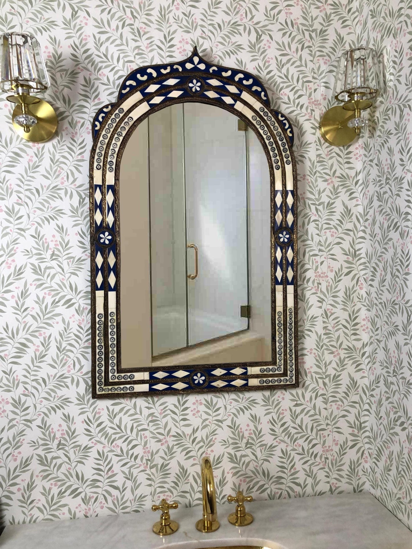 Arched inlay mirror with blue and ivory details in a bathroom.