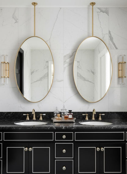 Double oval brass hanging mirrors over black vanity