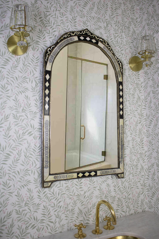 Side angle of an arched mirror with intricate black and ivory inlay details.