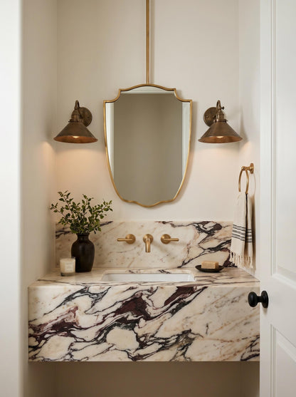 Suspended brass mirror above a marble vanity in a warm neutral bathroom.