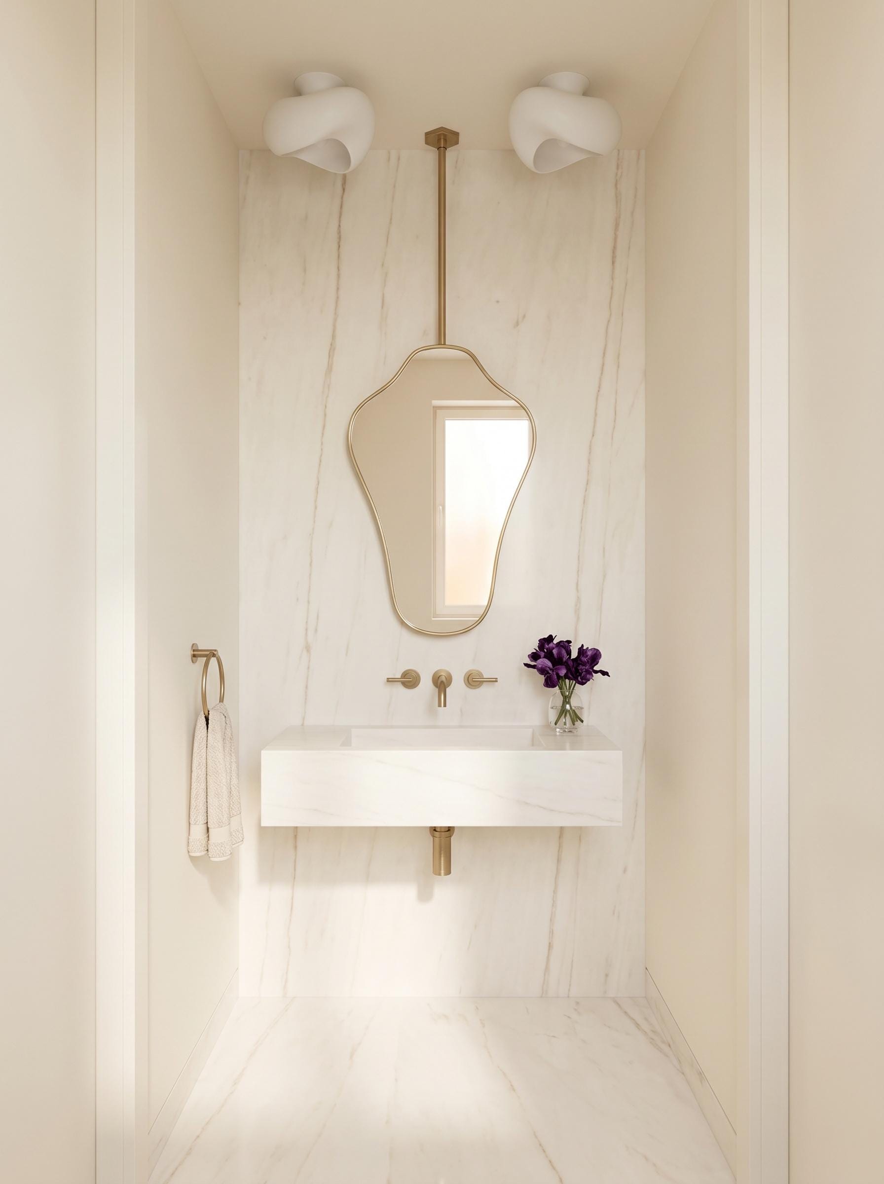 Modern hanging brass mirror in a minimalist white marble bathroom