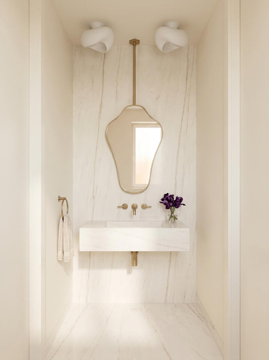 Modern hanging brass mirror in a minimalist white marble bathroom