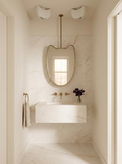 Modern suspended brass mirror in minimalist marble bathroom