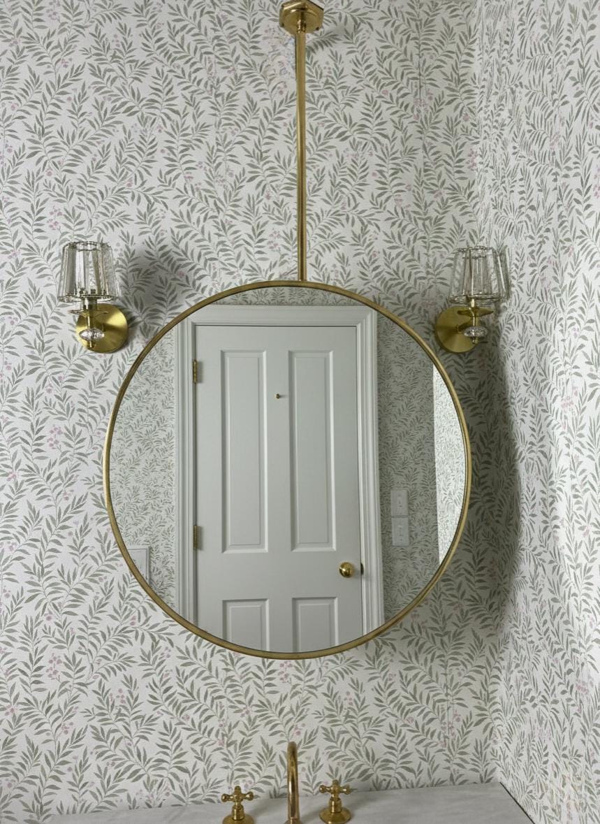Suspended round brass bathroom mirror with wall sconces