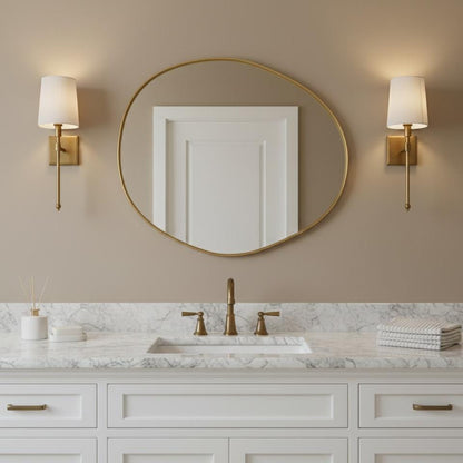 Irregular round brass bathroom vanity mirror above marble sink