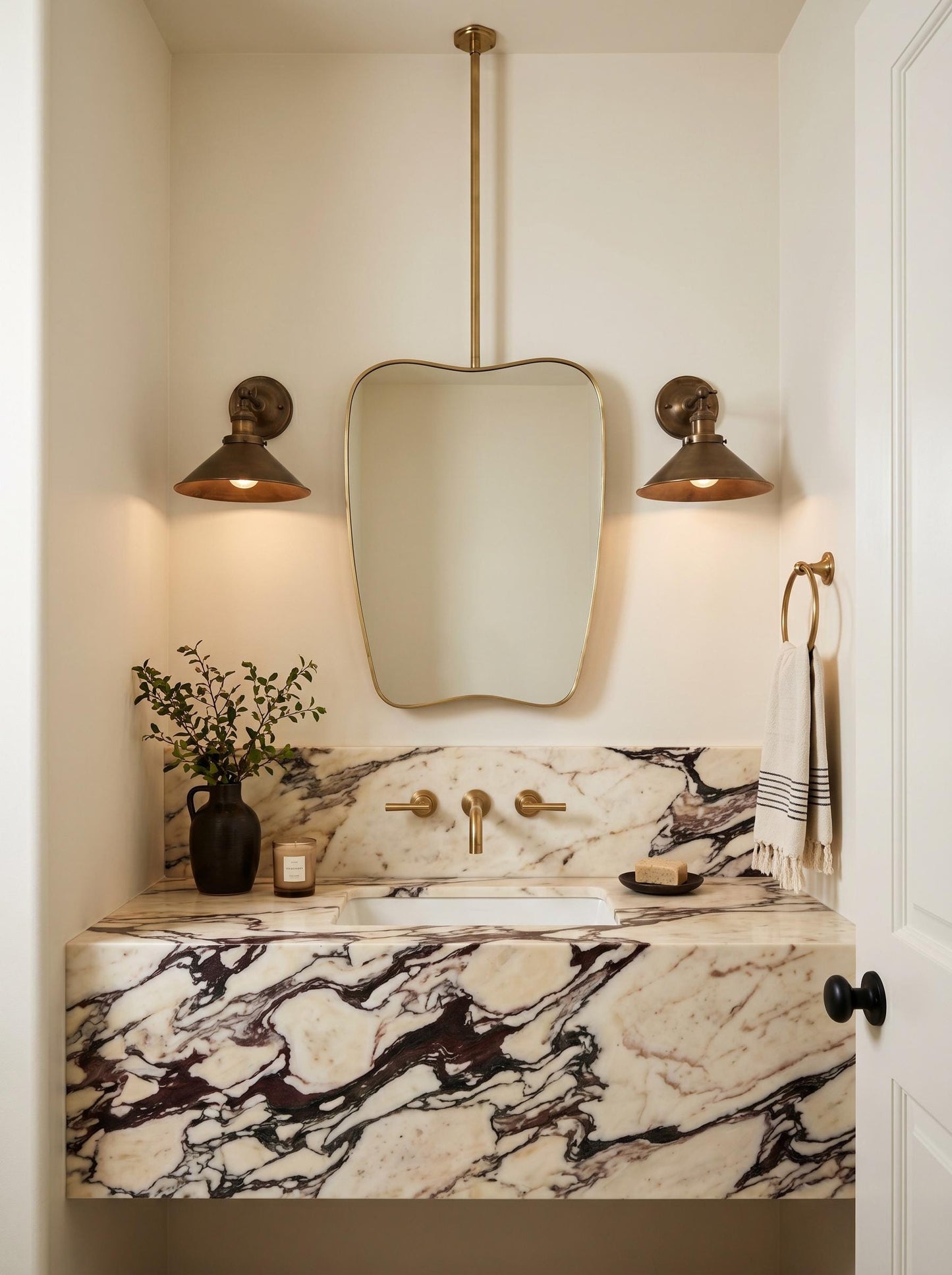Organic brass ceiling mounted mirror above floating white marble vanity