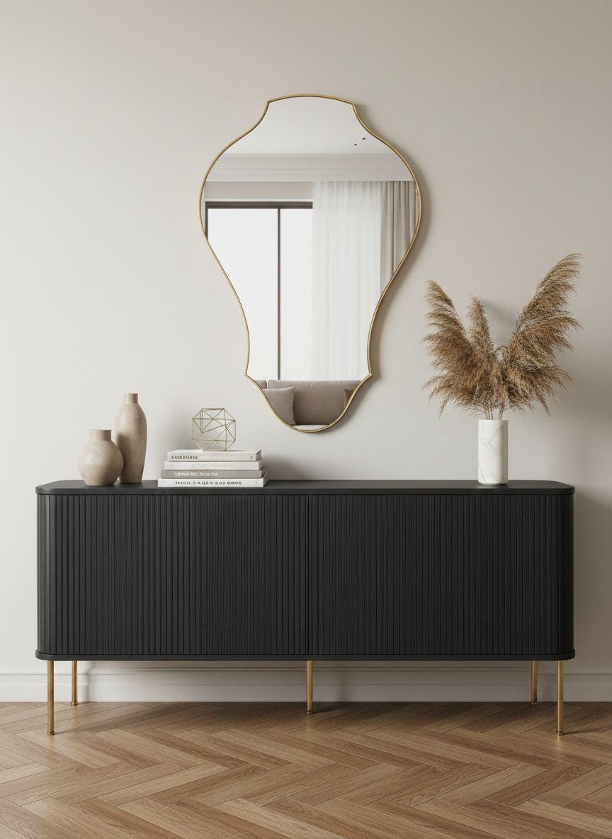 Curved sculptural brass wall mirror above black console