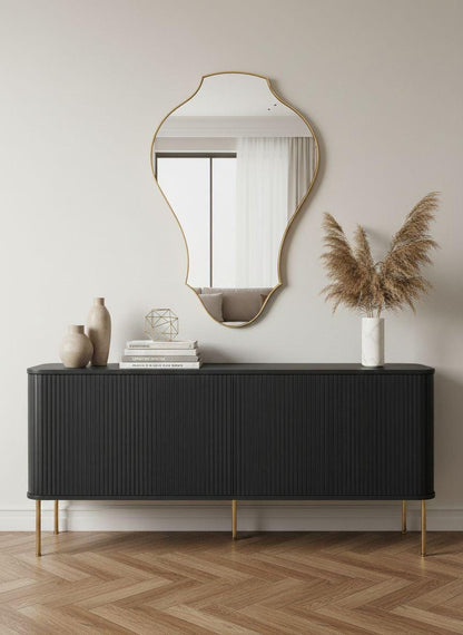 Curved sculptural brass wall mirror above black console