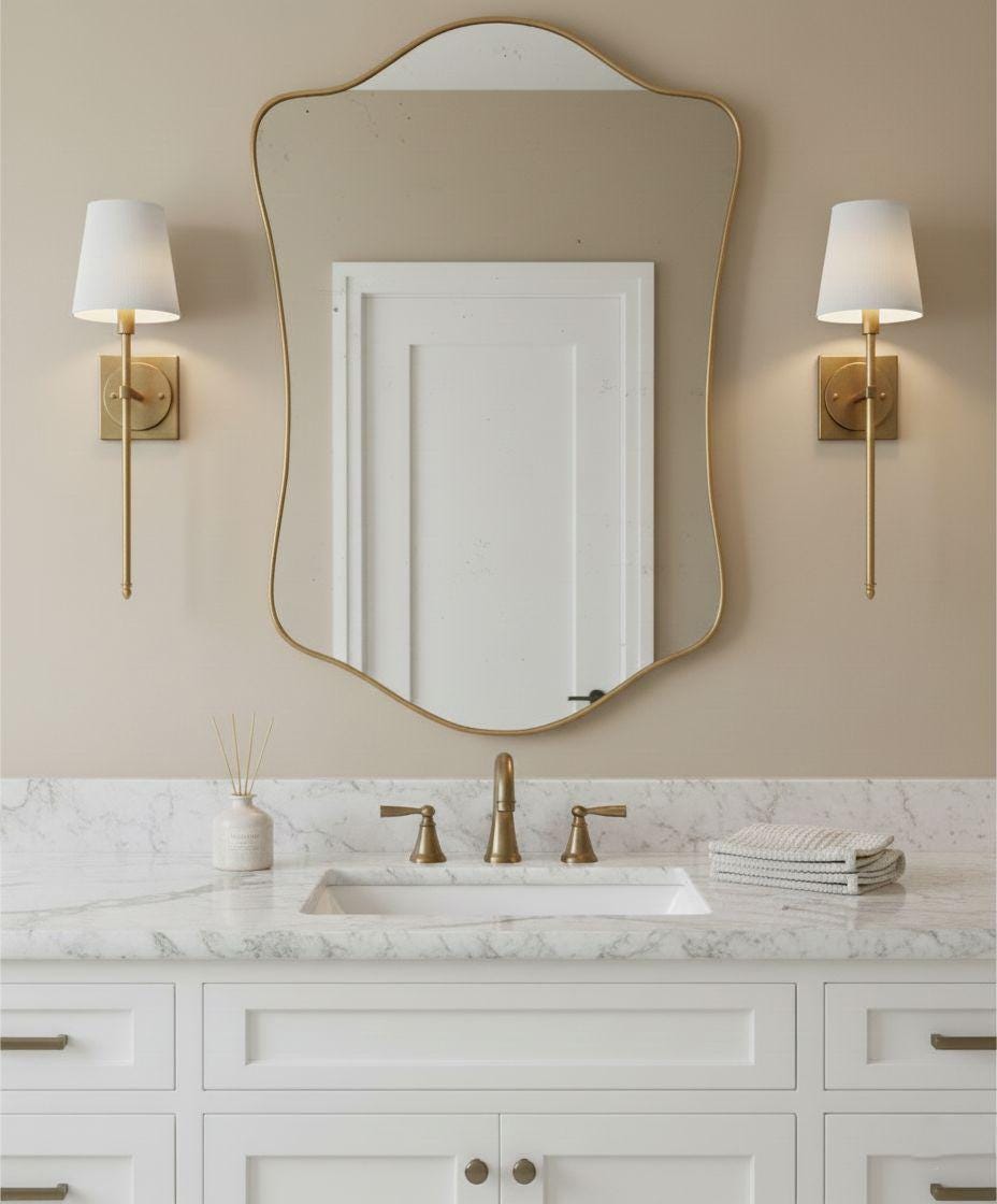 Curved irregular brass bathroom mirror above white vanity
