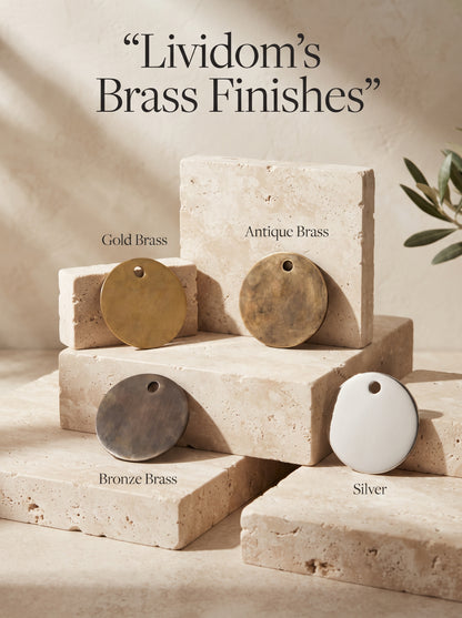 Four round finish samples labeled Gold Brass, Antique Brass, Bronze Brass, and Silver, arranged on beige stone blocks.