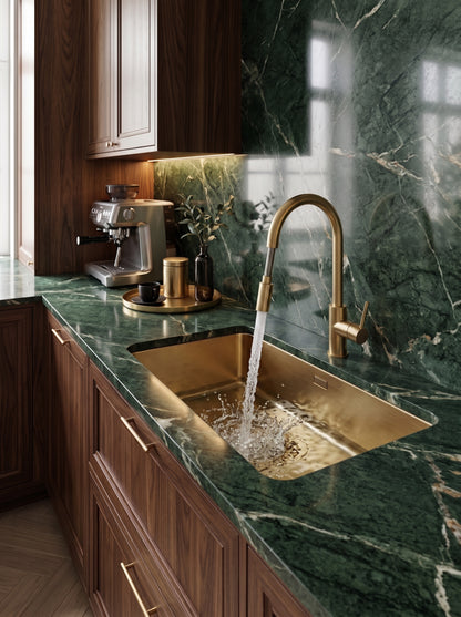 Brass pull-down faucet with water flowing into brass sink
