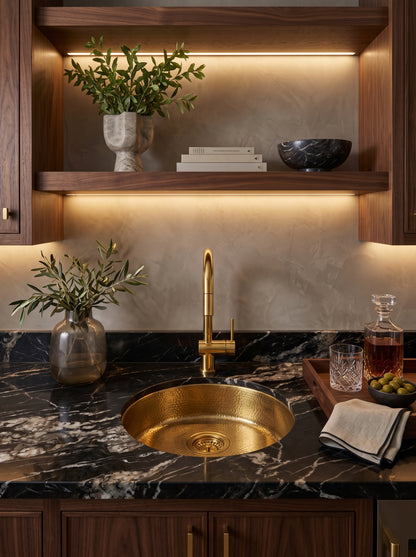 Unlacquered brass gooseneck faucet over hammered brass sink