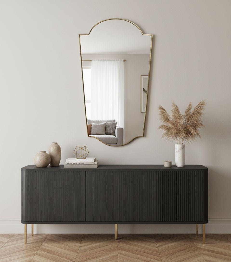 Modern shield-shaped brass wall mirror in living room