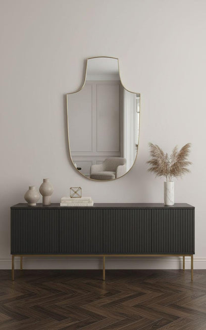 Handmade shield brass mirror styled above black sideboard