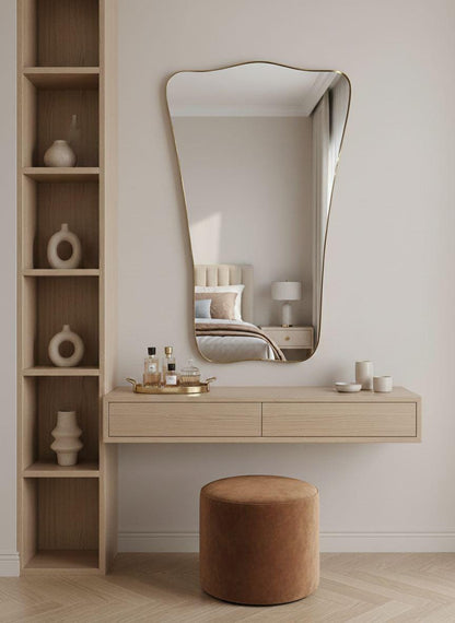 Organic asymmetrical brass mirror above bedroom vanity table