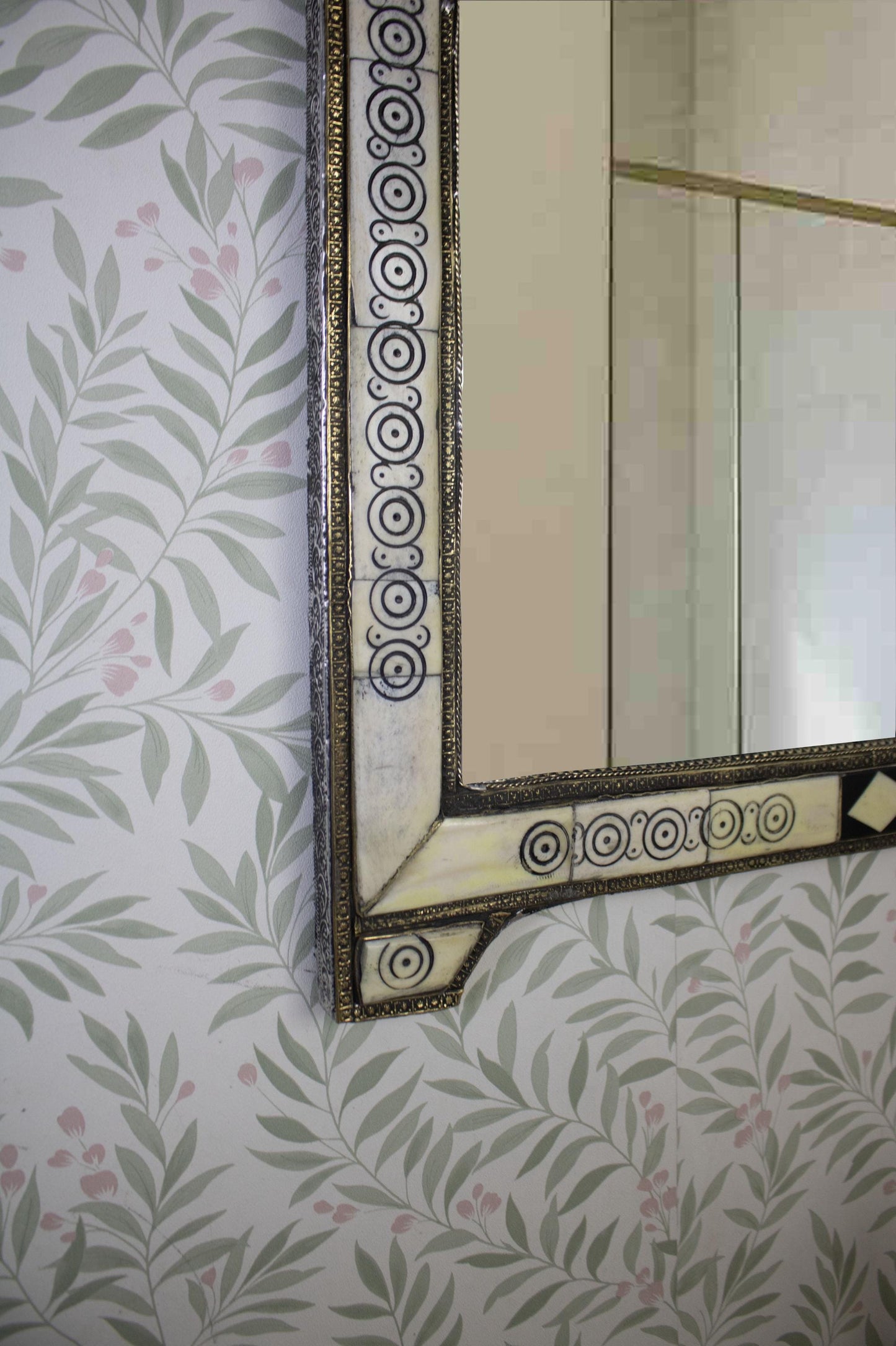 Detailed view of the lower left corner of the mirror with circular carvings.