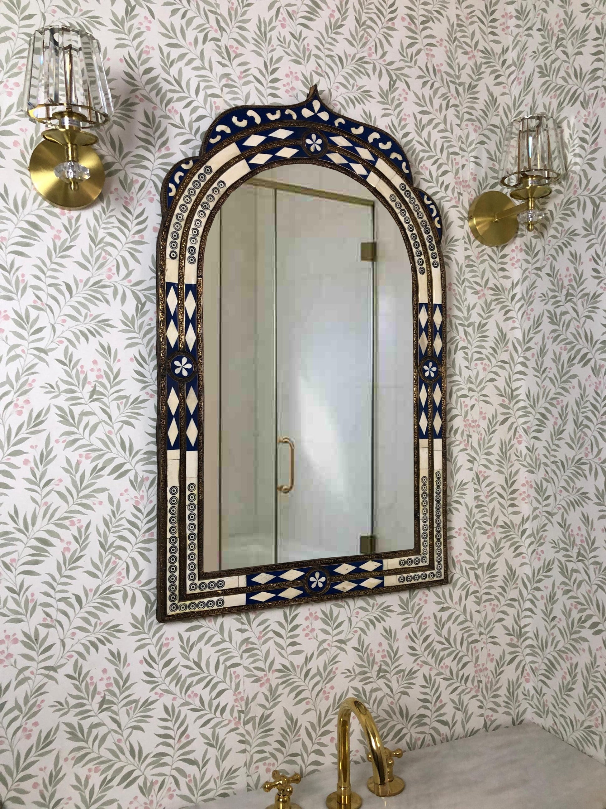 Bathroom view with blue and ivory inlay arched mirror over sink.