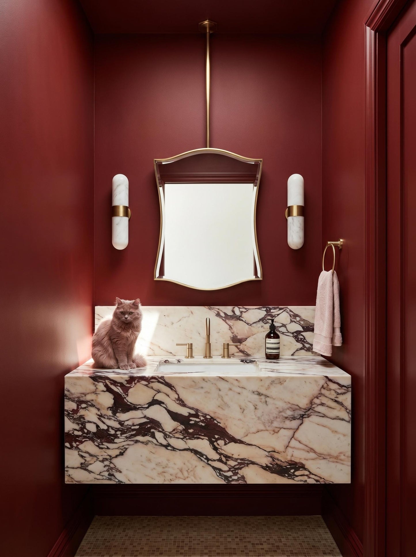 Curved brass hanging mirror in deep red luxury powder room