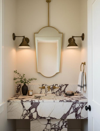 Brass shield mirror in red bathroom