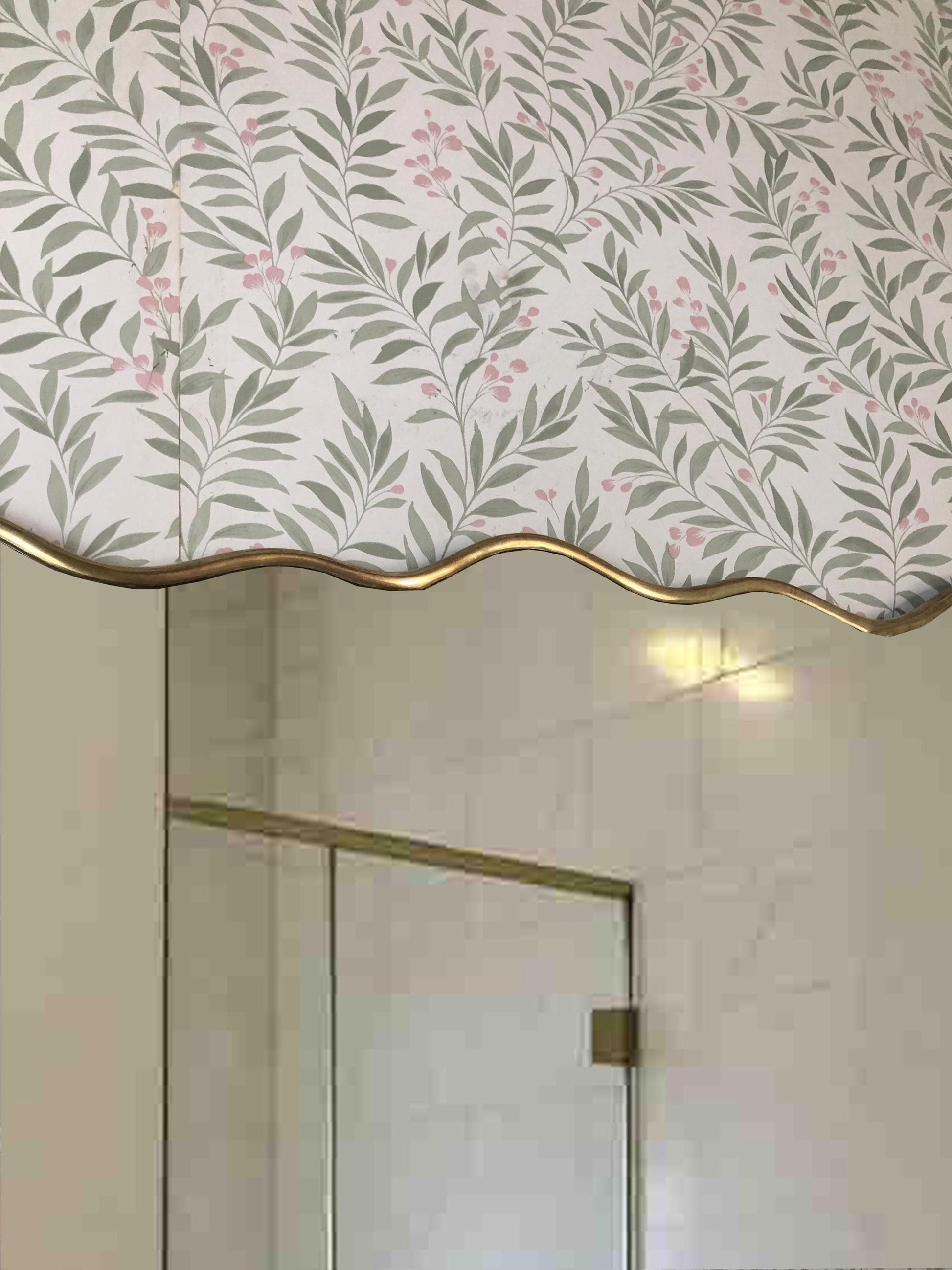 Close-up of brass-framed mirror with floral wallpaper background.