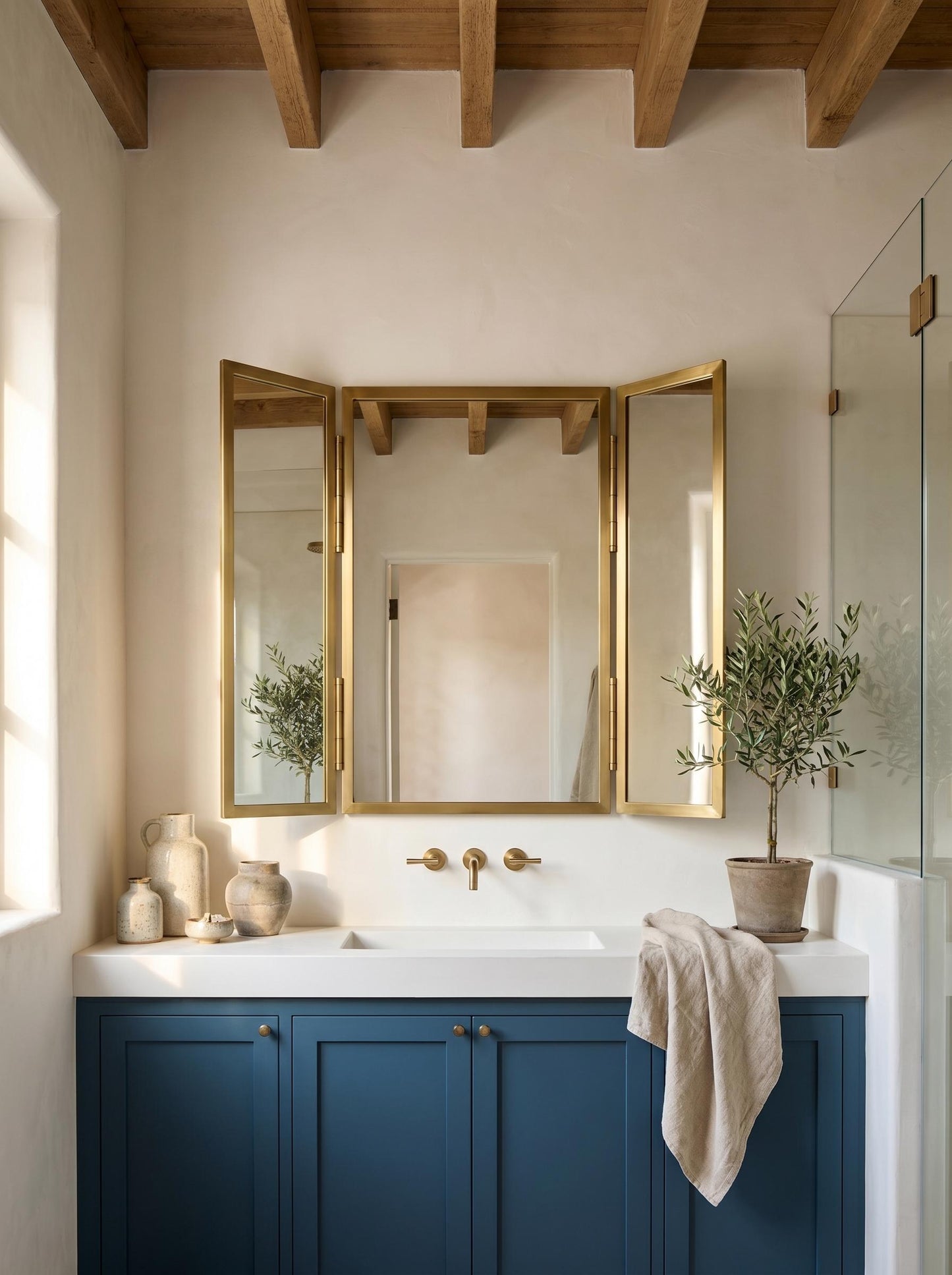 Brass trifold mirror above blue bathroom vanity.