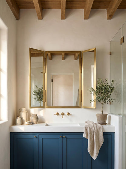 Brass trifold mirror above blue bathroom vanity.