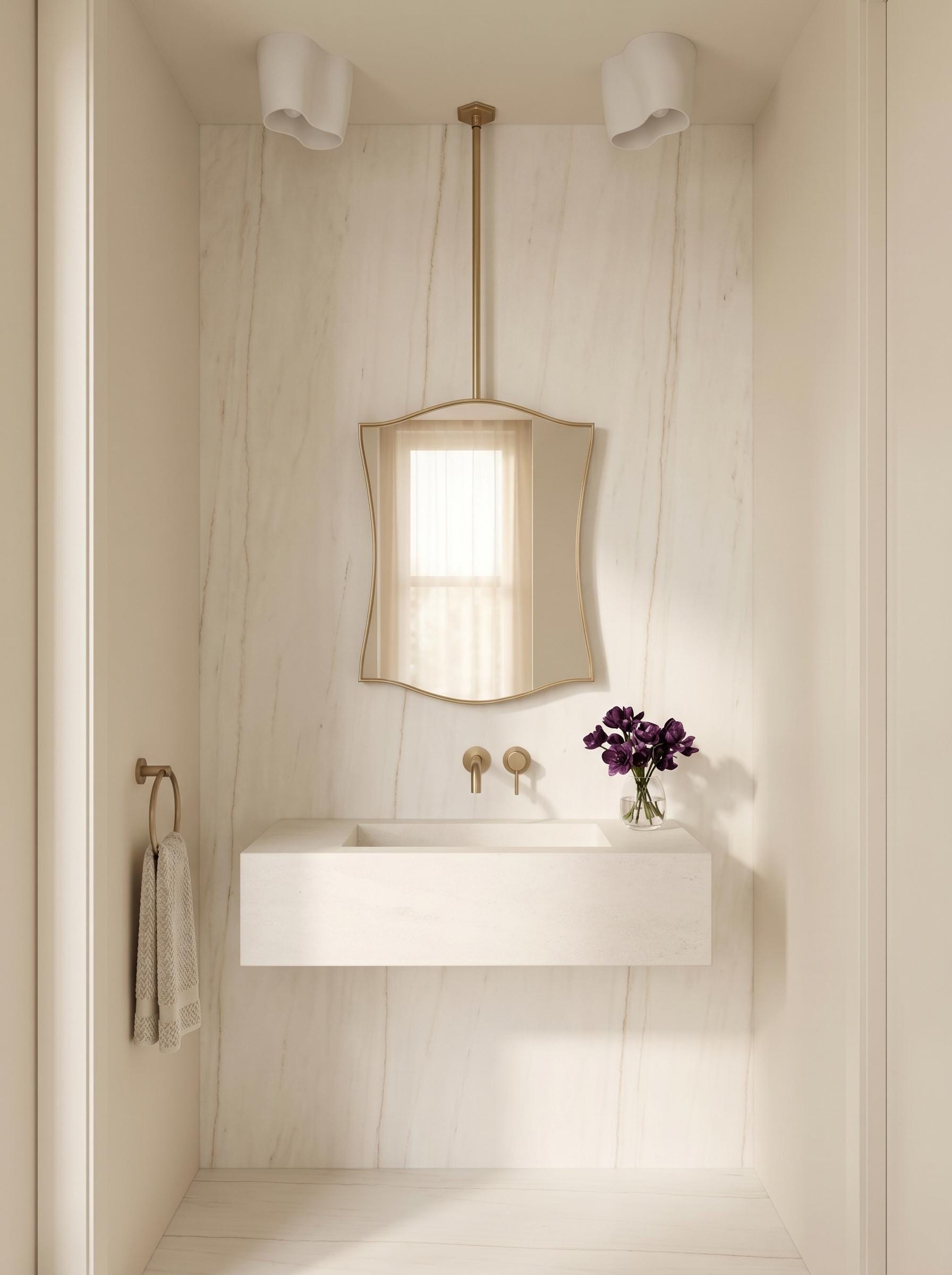 Hanging brass mirror above floating white stone vanity in minimalist bathroom