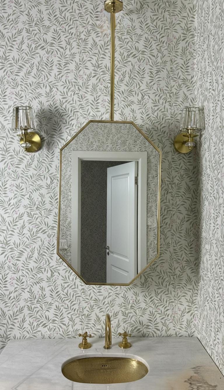 Modern brass hanging mirror above marble bathroom sink