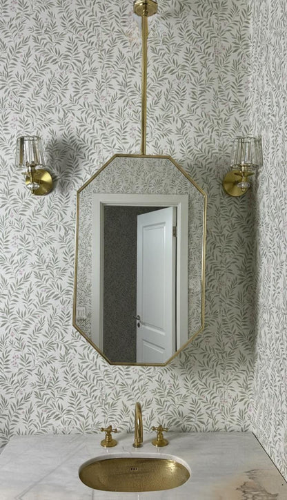 Modern brass hanging mirror above marble bathroom sink
