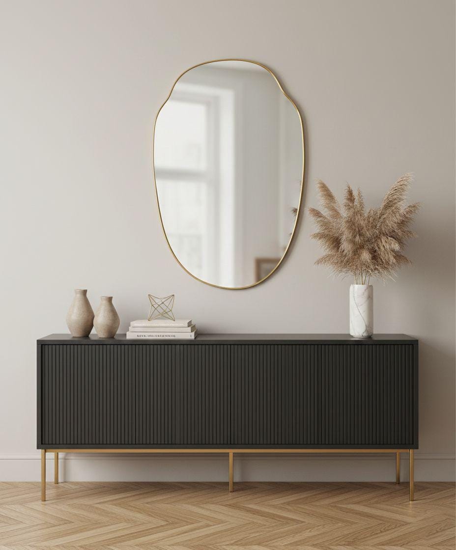 Asymmetrical oval brass wall mirror styled above black console