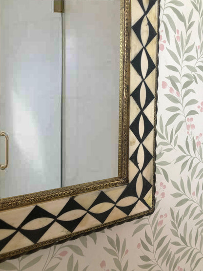Close-up of mirror corner showing intricate black and white pattern frame