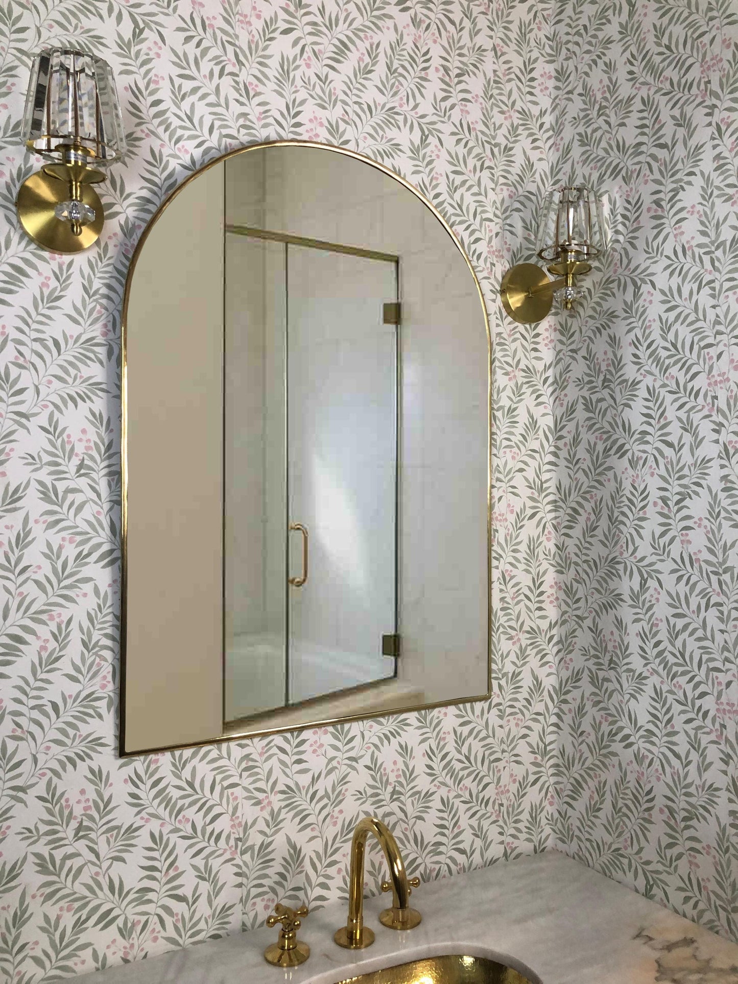 Unlacquered brass arch mirror over bathroom vanity.