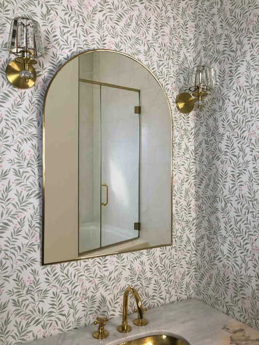 Unlacquered brass arch mirror over bathroom vanity.